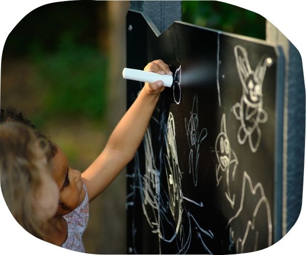 Child drawing on chalk board in a playground setting