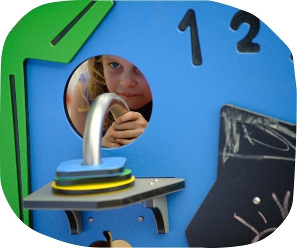 Child peering through playground equipment